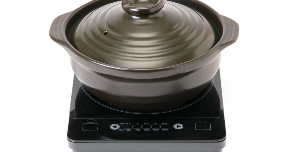 IH一口コンロの上に、蓋つきの黒い土鍋が置かれている様子。